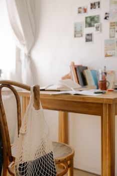 Rustic wooden desk in cozy home office with books and net bag. Ideal for studying or working.