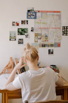 一名学生专注地坐在课桌前学习，周围摆满了书籍和海报