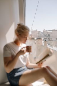 Reader with a mug beside a window — photo by cottonbro studio on Pexels
