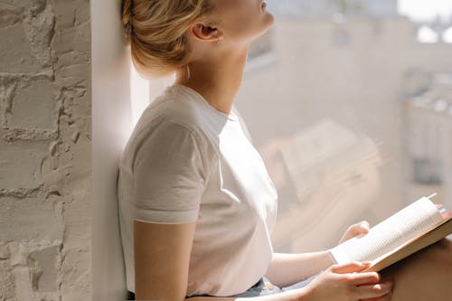 Free Woman in White T-shirt and Blue Denim Shorts Sitting on Window Stock Photo