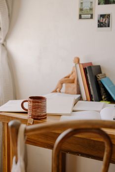 Inviting workspace with books, an open notebook, and a warm mug of tea on a wooden desk.