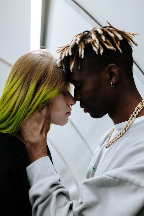 бесплатная Мужчина в белой рубашке целует женщину с зелеными волосами Стоковое фото