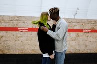Man and Woman Kissing Near White Wall