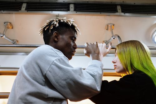 Free A young couple stands face to face on a subway train, engaging in conversation. Stock Photo