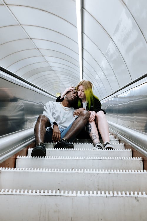 Man and Woman Sitting on Escalator