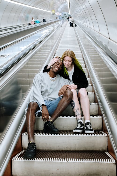 Free Man and Woman Sitting on Escalator Stock Photo