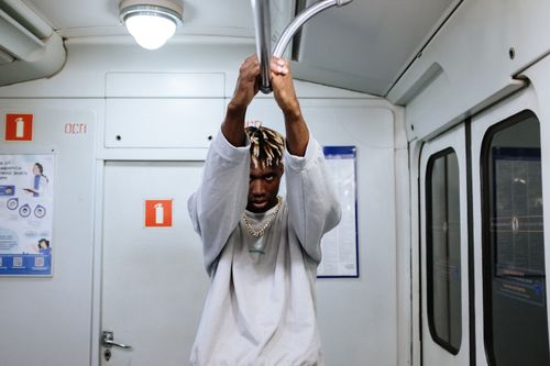 Free Fashionable young man with dreadlocks poses on subway train, conveying urban style and attitude. Stock Photo