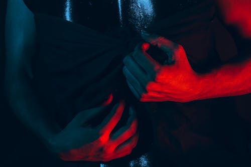 Free Crop anonymous person touching dark fabric with delicate hands illuminated by red light Stock Photo