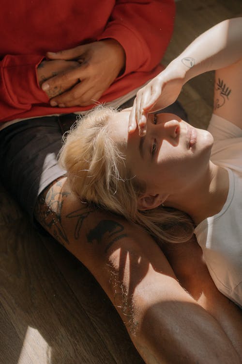 Woman in White Tank Top Lying on Brown Textile