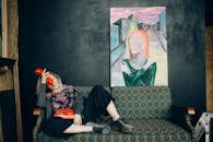 一位妇女懒洋洋地坐在一张老式沙发上，手里拿着一个经典红色电话，背景是反对艺术