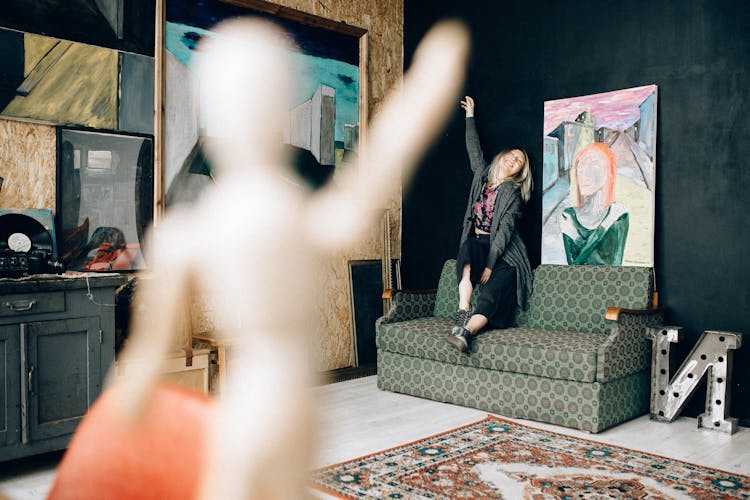 A Woman Sitting On A Couch With Her Hand Up