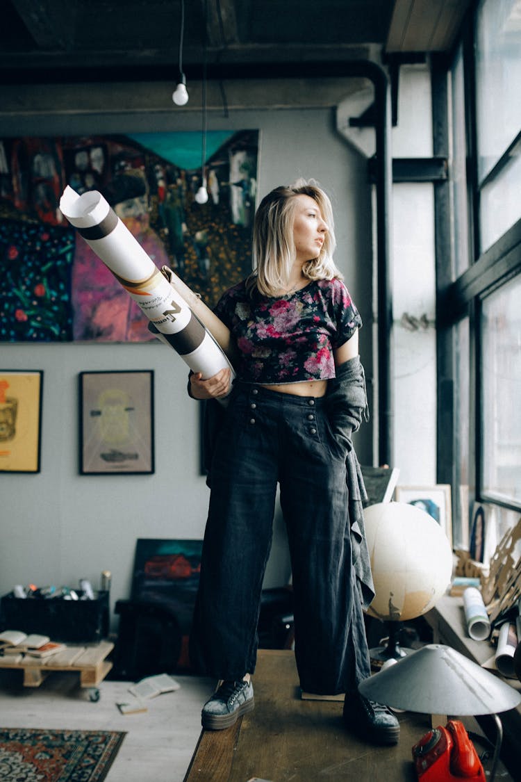 A Young Woman In Printed Crop Top Standing And Holding A Roll Poster