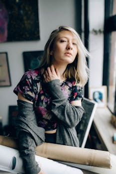 Portrait of a young woman artist holding art supplies in an indoor studio setting, exuding creativity.