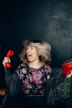 一个女人对着室内一部老式红色电话愤怒地大喊大叫