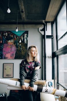 在一间有着大窗户和充满活力画作的现代城市工作室里，一位年轻的女艺术家正拿着艺术用品
