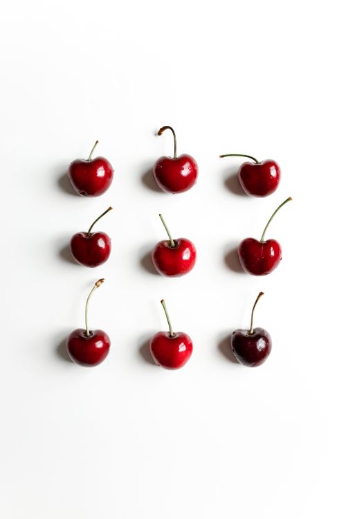 Free Arrangement of nine red cherries on a white background, showcasing a minimalist flatlay style. Stock Photo