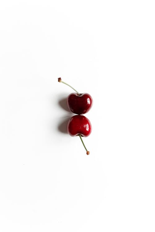 Two Red Cherries on White Surface