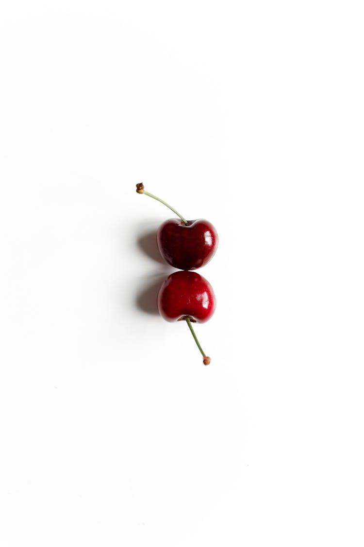 Two Red Cherries On White Surface