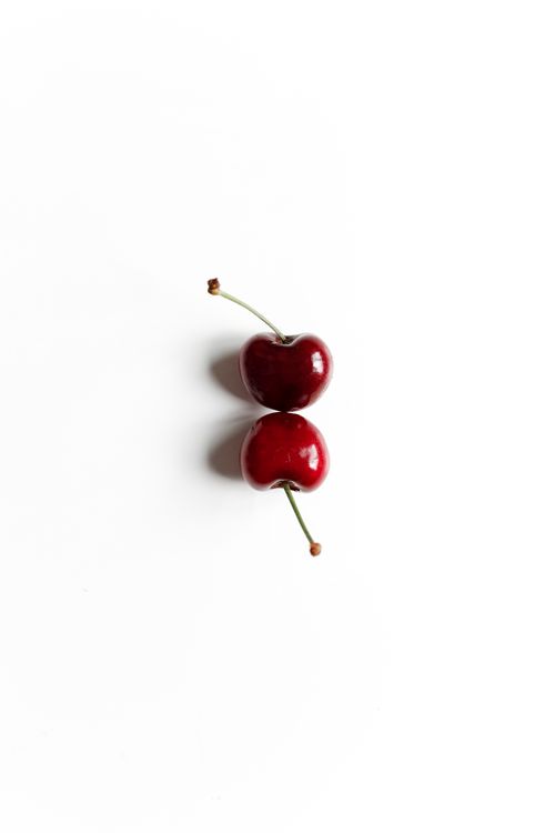 Free A minimalist display of two ripe cherries on a clean white surface, showcasing simplicity and elegance. Stock Photo
