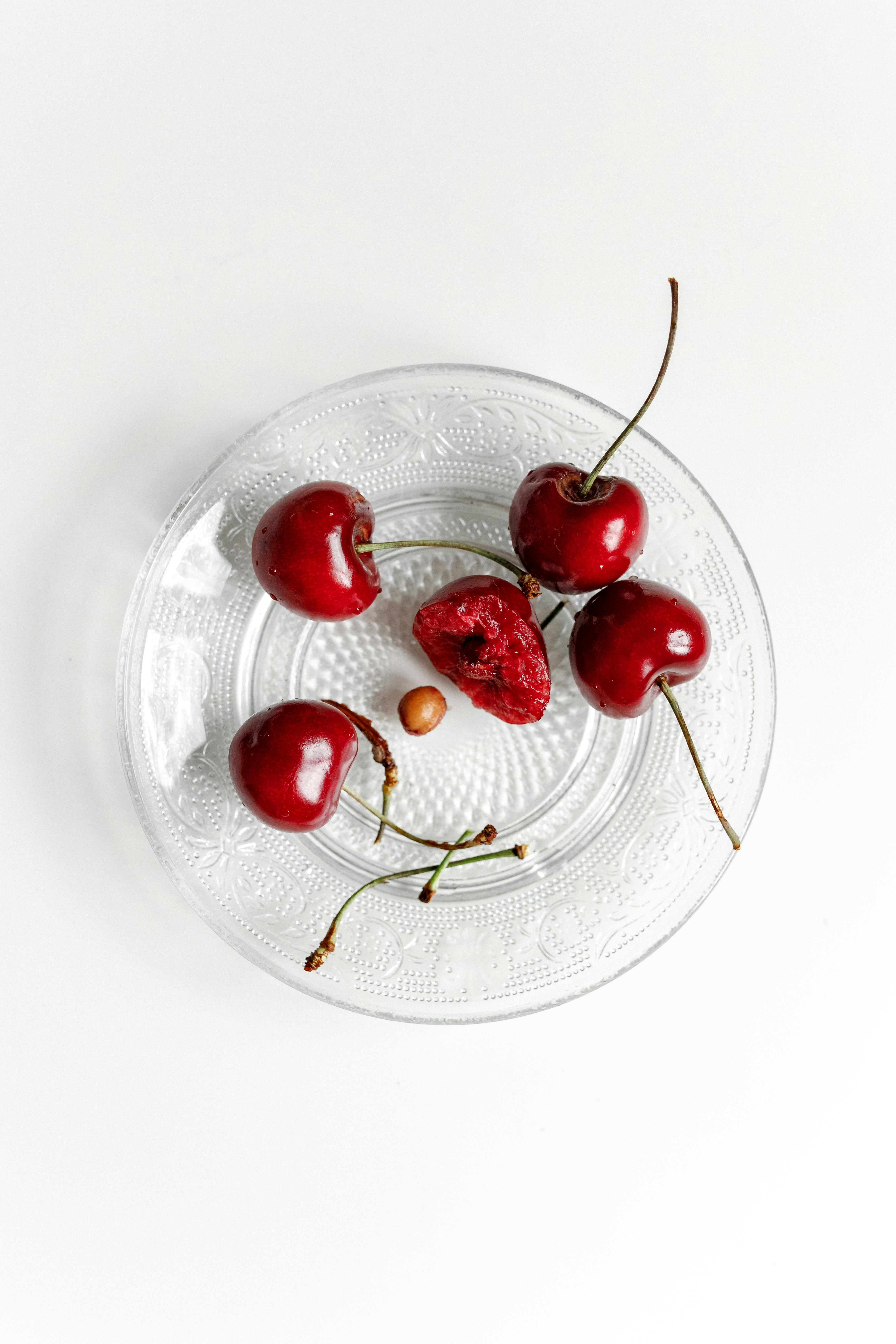 red cherries on clear glass plate