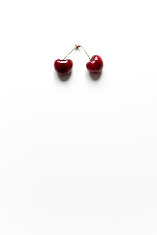 Two Cherries on White Surface