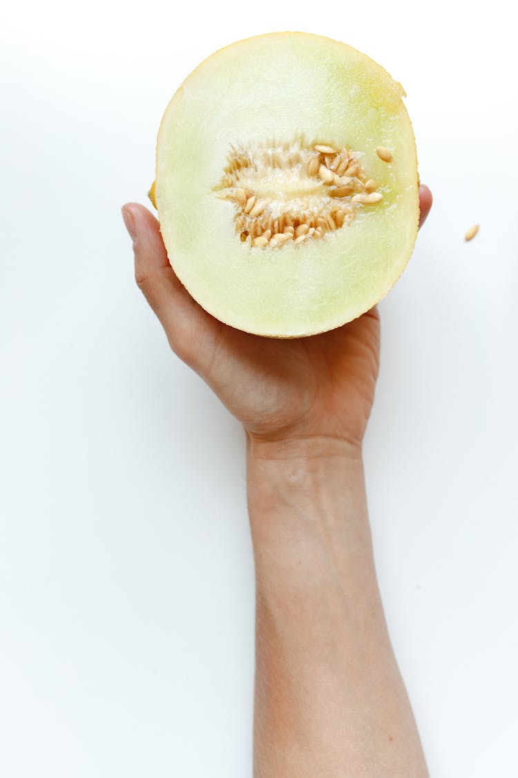 Man Hand Holding A Half Cut Melon