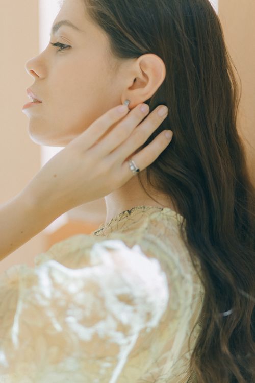 Free Side profile of an elegant woman with long hair touching her ear in soft natural light. Stock Photo