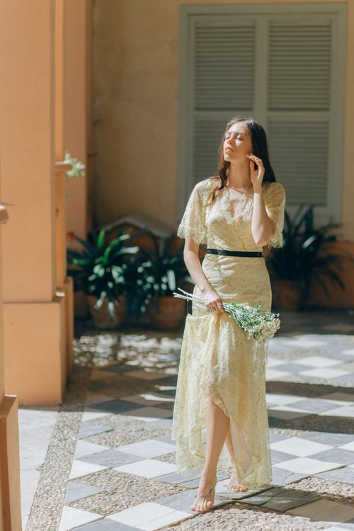 Free Graceful woman in a lacy dress standing barefoot indoors with flowers. Stock Photo
