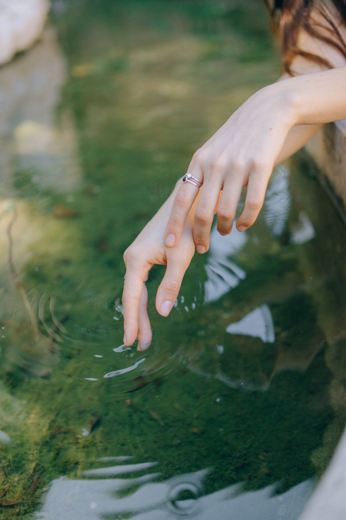 A hand touching a green water surface, sending out ripples — photo by Nataliya Vaitkevich on Pexels