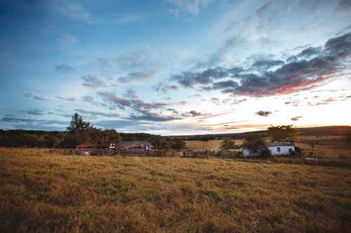 Free Light blue sky covered with pink highlighted clouds above building and grassland in countryside in evening Stock Photo