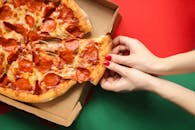 在充满活力的红绿背景下，特写镜头从盒子中取出意大利辣香肠披萨片