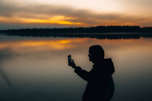 Free Silhouette of Person Holding Smartphone Stock Photo