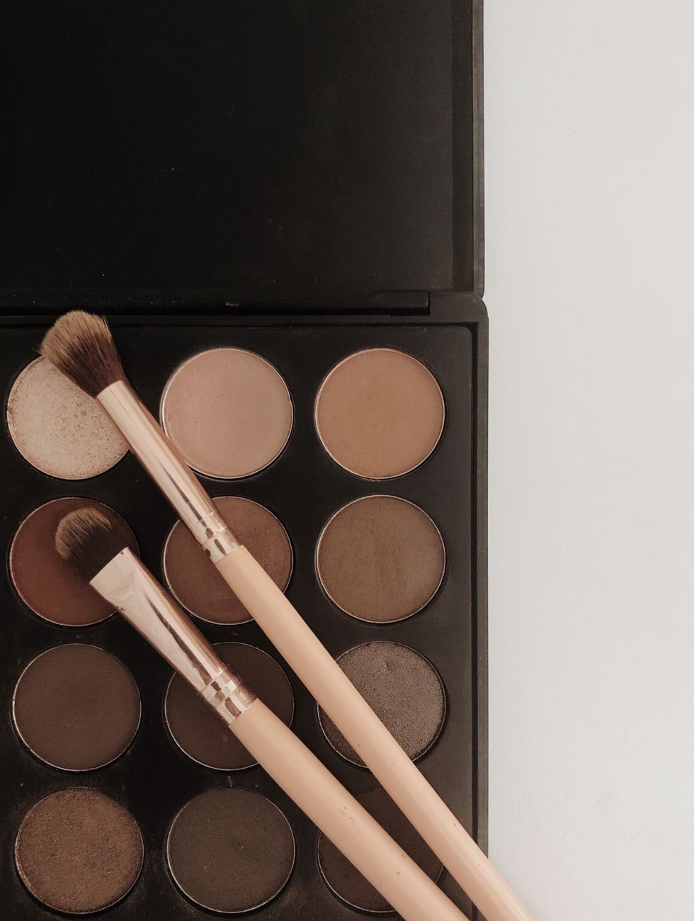 A neutral eyeshadow palette with makeup brushes arranged on top, perfect for beauty and cosmetics themes.. pexels, neutral, e