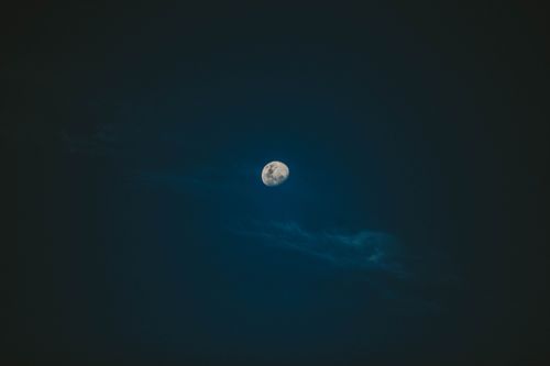 Free Grey round waning Moon covered with craters surrounded by clouds in dark blue sky at night Stock Photo