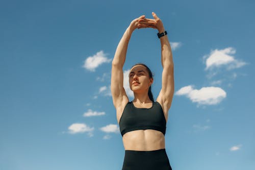 Free Woman in Black Sports Bra and Black Shorts Raising Her Hands Up Stock Photo