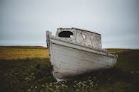 Old boat on grassy field in overcast
