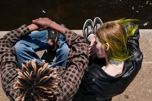 从空中俯瞰，一对发型独特的年轻夫妇坐在城市水边