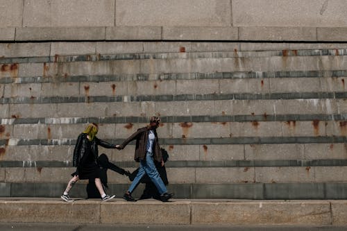 黑色外套和藍色牛仔牛仔褲，在灰色的混凝土樓梯上行走的女人