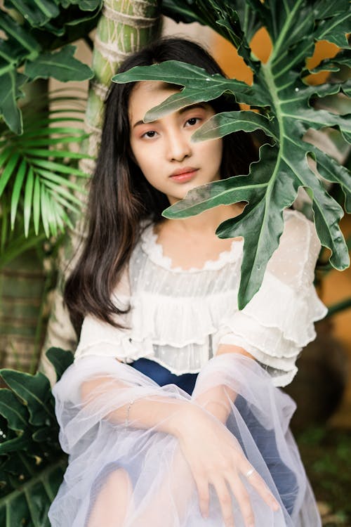 Photo of a Girl Posing Near Green Leaves