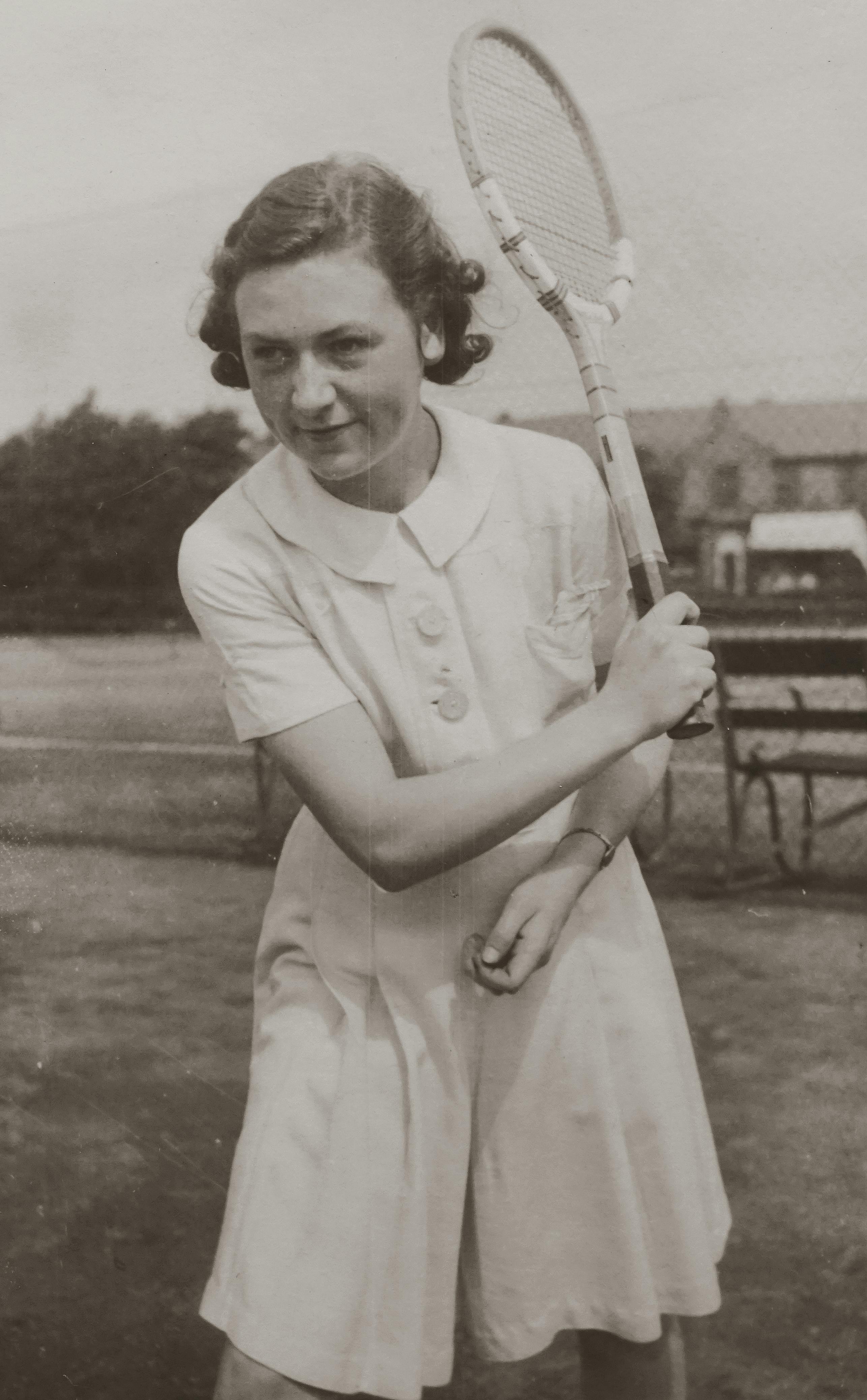 Historic black and white photo of a young woman playing tennis, capturing vintage sports style.