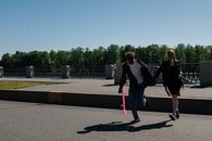Woman in Black Jacket and Pink Pants Walking on Gray Concrete Pathway