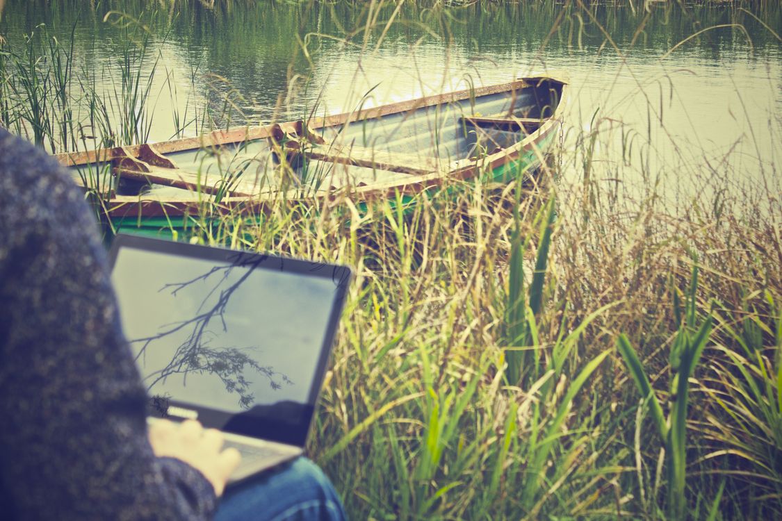 Using Computer Outside Person Using Black Laptop Computer Near Green Boat · Free Stock Photo