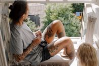 Woman in White T-shirt and Black Shorts Sitting on Brown Wooden Bench
