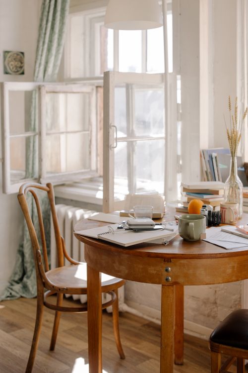 Free A beautifully disordered dining area with an open window, wooden table, and decorative items. Stock Photo