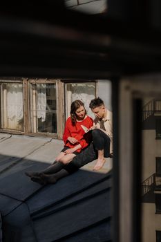 一对年轻夫妇在屋顶上读书，享受户外明媚的阳光