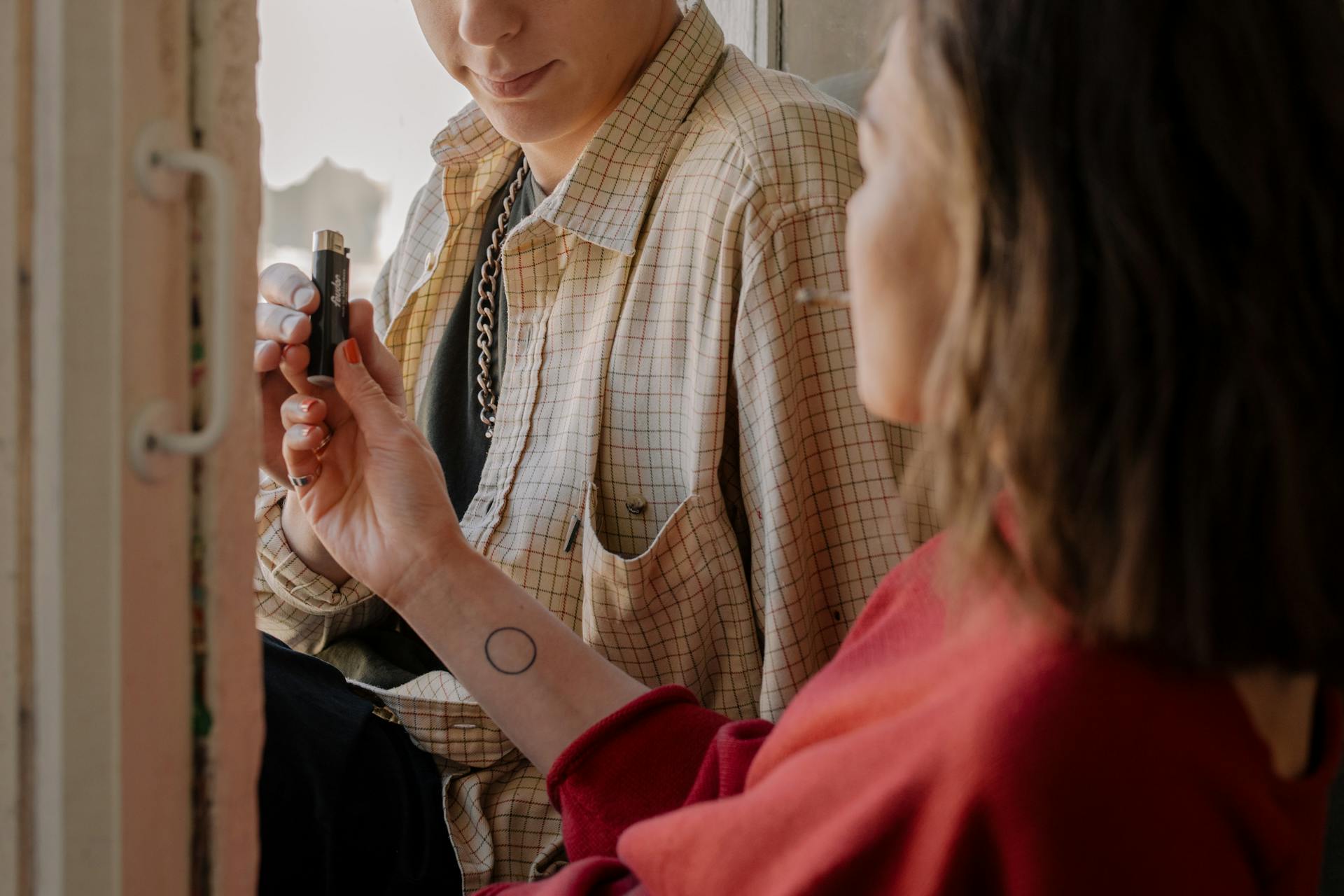 Woman in Brown and White Plaid Button Up Shirt Holding Black Bottle