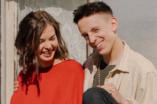 Woman in Red Knit Sweater Smiling Beside Man in Black Jacket