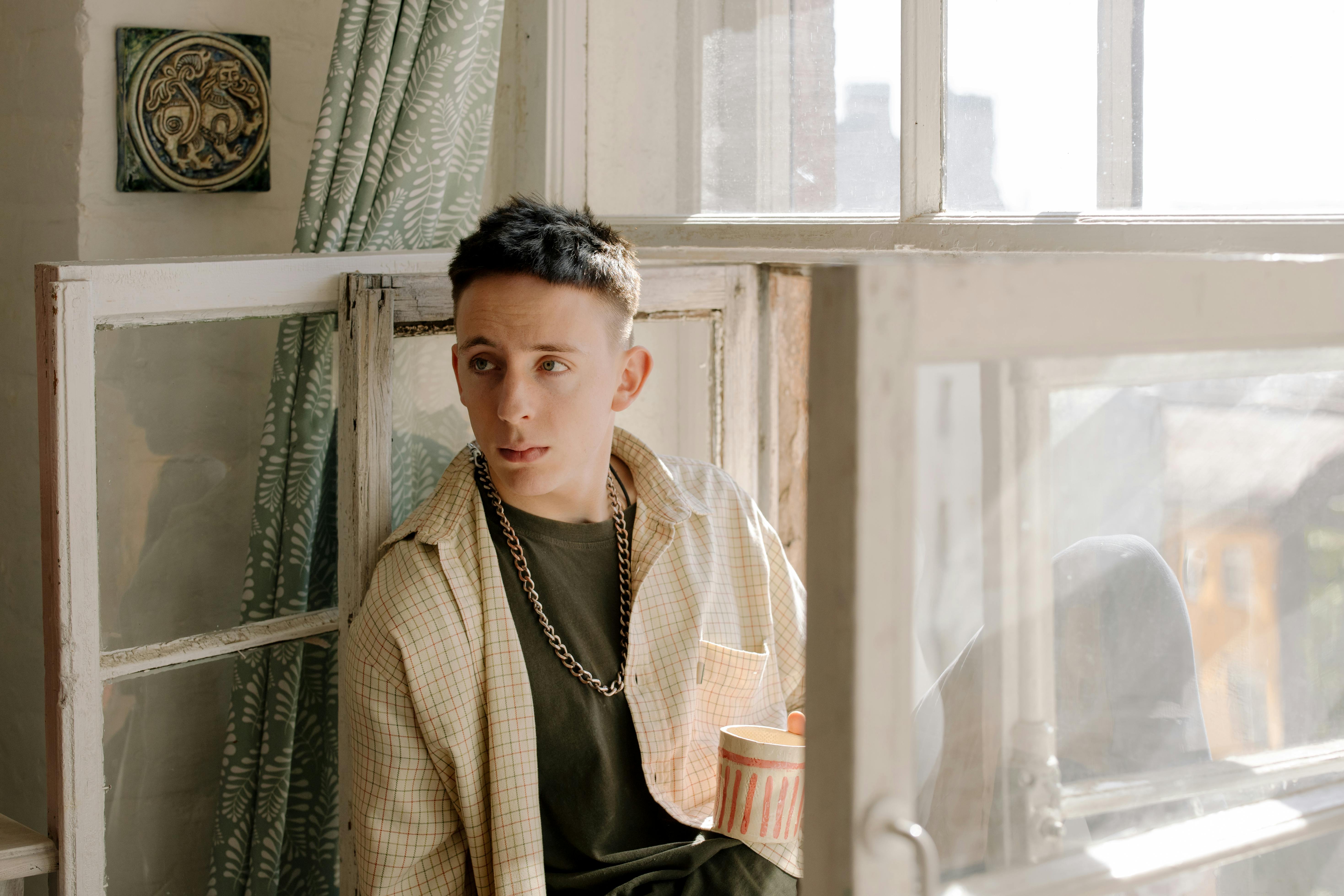 一个年轻人在窗边喝着咖啡，享受休闲时光