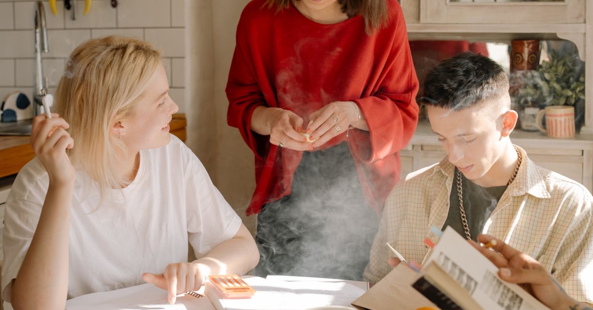 A group of students laughing in a hostel kitchen near HTU, making pasta