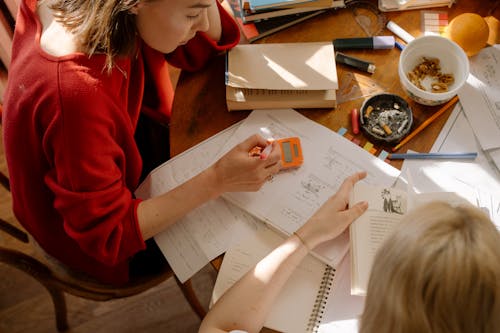 Girl in Red Long Sleeve Shirt Writing on White Paper